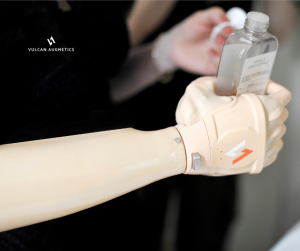 A female arm amputee is wearing a fair skin Vulcan prosthetic hand to hold a cleanser